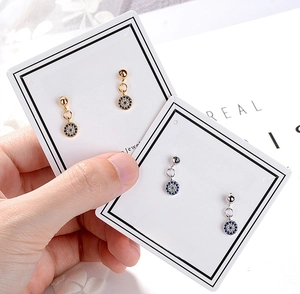 Close-up of gold and silver evil eye drop earrings with blue and white crystals