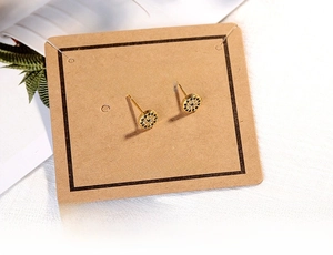 Detail of gold evil eye stud earrings with blue and white zircons on luxury card