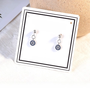 Detailed view of silver evil eye stud earrings with blue and white pavé crystals on card