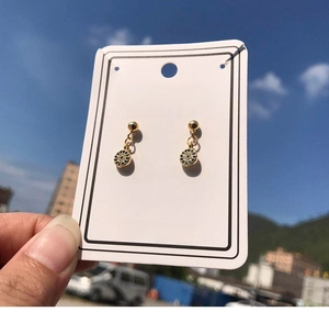Detail showing gold evil eye earrings with blue crystals held against the blue sky