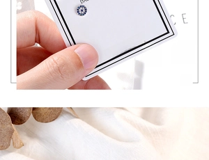 Close-up of Evil Eye stud earring with blue and white zircons on a jewelry card