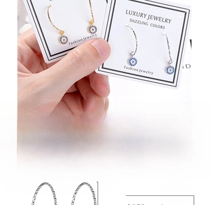 Detailed view of evil eye hoop earrings with blue stones and white crystals in gold and silver