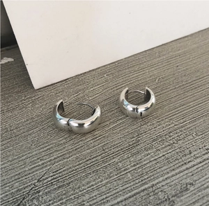 Macro detail of chunky silver 925 sterling silver hoop earrings with a polished metal finish