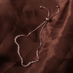 Detail of rose gold adjustable bracelet with sparkling rhinestones on brown silk background