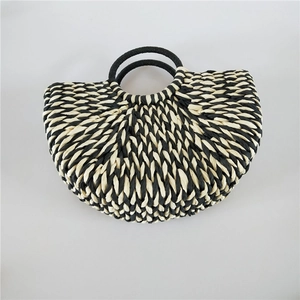 Detail view of woven textures on a bicolor straw handbag with black and white patterns