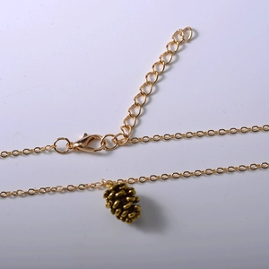 Makroaufnahme einer goldenen Gliederkette mit Kiefernzapfen-Anhänger und Karabinerverschluss