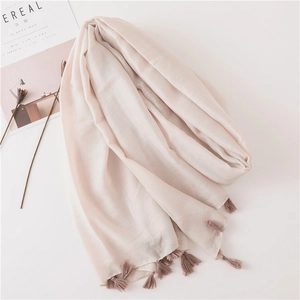 Detailed view of soft linen texture and fringe trim on a pinkish beige scarf