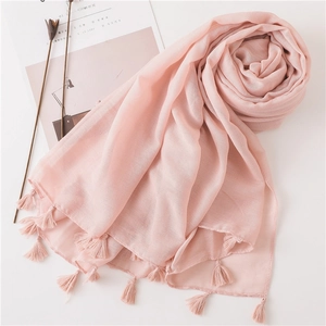 Detail of light pink cotton linen scarf featuring elegant fringe tassels and soft texture