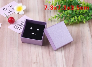 Top view of purple square jewelry box with ring and earrings on wood background