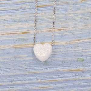 Macro shot of silver heart pendant with white opal showing rainbow color play