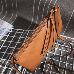 Detail of brown faux leather crossbody bag texture with gold zipper and knotted strap