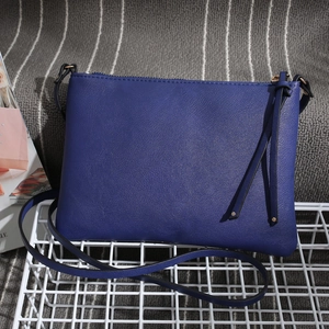 Detail of dark blue PU leather envelope bag with matching fringe tassels and shoulder strap