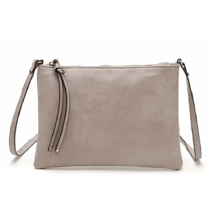 Light taupe faux leather crossbody clutch bag with tassel detail on white background