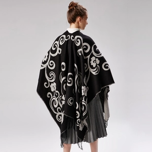 Close-up of bohemian floral knit pattern and fringe detail on thick winter shawl