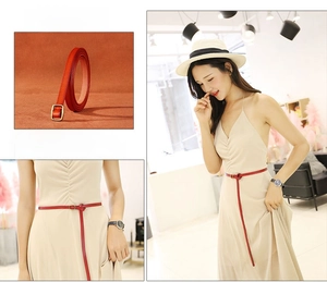 Detail view of slim red leather belt with golden square buckle on a beige dress