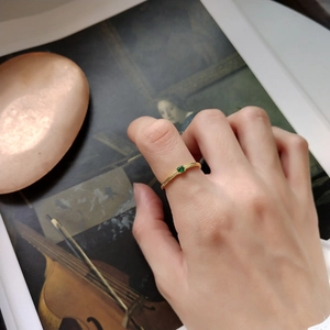 Close-up of vintage 925 silver gold ring with green gemstone on a model's finger