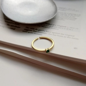 Detailed close-up of a gold 925 silver ring with a green square gemstone on an open book