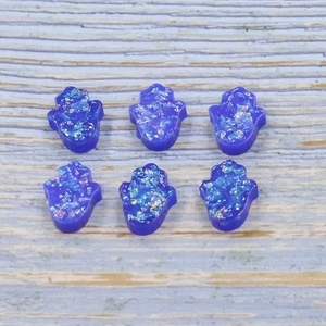 Macro view of blue resin Hamsa Opal palms with colorful holographic glitter flakes