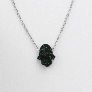 Macro shot of black Hamsa hand pendant with blue-green opal inlay on a silver chain