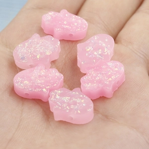 Close-up of six pink glittery Hamsa hand charms for DIY jewelry making accessories