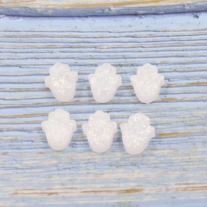 Close-up of white Hamsa beads with glitter effect on blue wood texture background