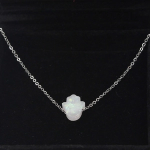 Macro shot of white synthetic opal Hamsa hand pendant necklace in black velvet box