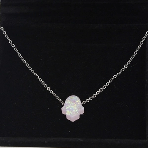 Pink Hamsa Hand pendant necklace with synthetic opal on a black velvet display stand