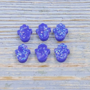 Close-up of purple synthetic opal Hamsa hand beads for DIY jewelry with shiny flakes