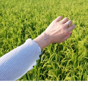 Detailed view of silver evil eye bracelet and ring on wrist with natural green background