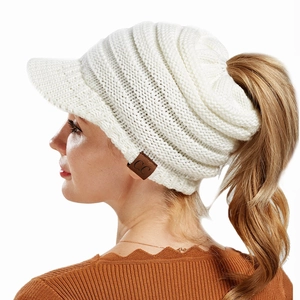 Detail of white knit ponytail beanie featuring curved brim and brown leather C.C label
