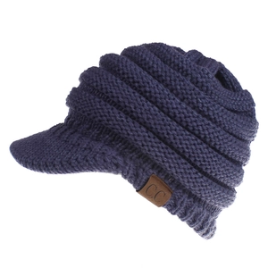 Close-up of navy blue knit ponytail beanie with C.C leather patch and visor brim