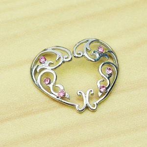 Silver hollow heart nipple clamp with pink rhinestones on a natural wooden background