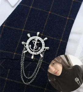 Détail d'une broche nautique avec gouvernail, ancre et chaînes sur revers de costume