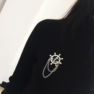 Broche nautique argentée avec gouvernail, ancre et chaînes sur costume noir