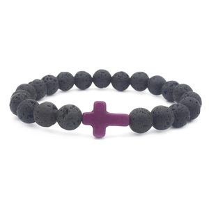 Macro shot of natural black volcanic lava beads featuring a purple cross charm bracelet