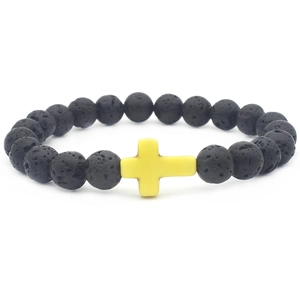 Close-up of black volcanic lava beads and yellow cross pendant on elastic bracelet