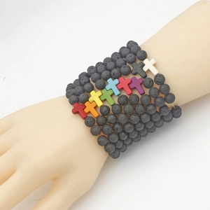 Lava stone bead bracelets with colorful crosses shown stacked on a model wrist