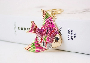 Detailed shot of tropical fish keychain with pink and green rhinestones on white book