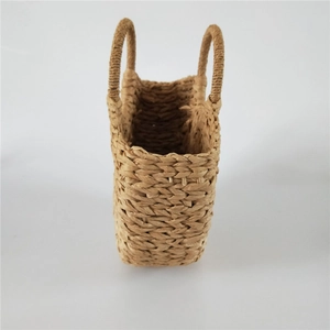 Detail of hand-woven straw basket bag with dual handles in natural dark beige finish