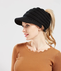Detail of black knit ponytail beanie with classic brown C.C leather label and ribbed texture
