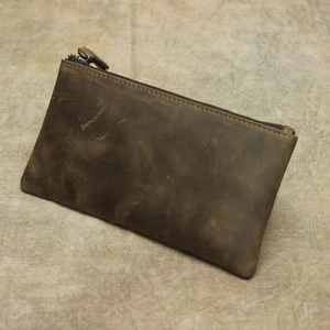 Close-up of vintage dark brown crazy horse leather wallet with textured grain and zipper
