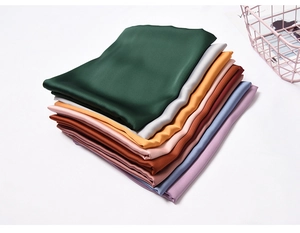 Detailed view of stacked colorful satin silk scarves with premium glossy texture