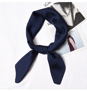 Detailed view of the smooth navy blue satin fabric texture on a knotted silk neck scarf