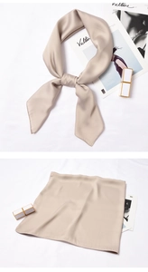 Detail of champagne silk scarf showing elegant bow knot and smooth satin texture finish