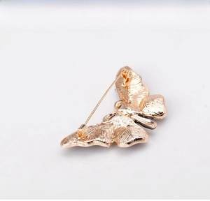 Detail view showing the golden back and secure pin closure of the butterfly brooch