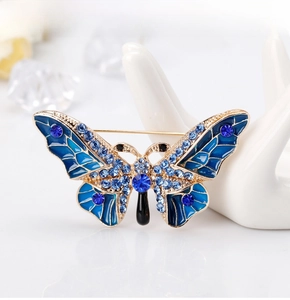 Close-up of golden enamel butterfly brooch with blue rhinestones on a white hand model