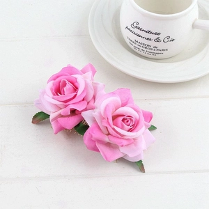 Detail view of pink velvet rose hair comb with green leaves on golden metal teeth