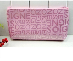 Close-up of pink rectangular vanity bag with jacquard letter patterns on a white counter