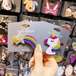 Detailed close-up of rainbow shooting star and unicorn glitter hair clips on card