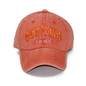 Close-up of orange washed cotton baseball cap featuring 3D New York embroidery detail